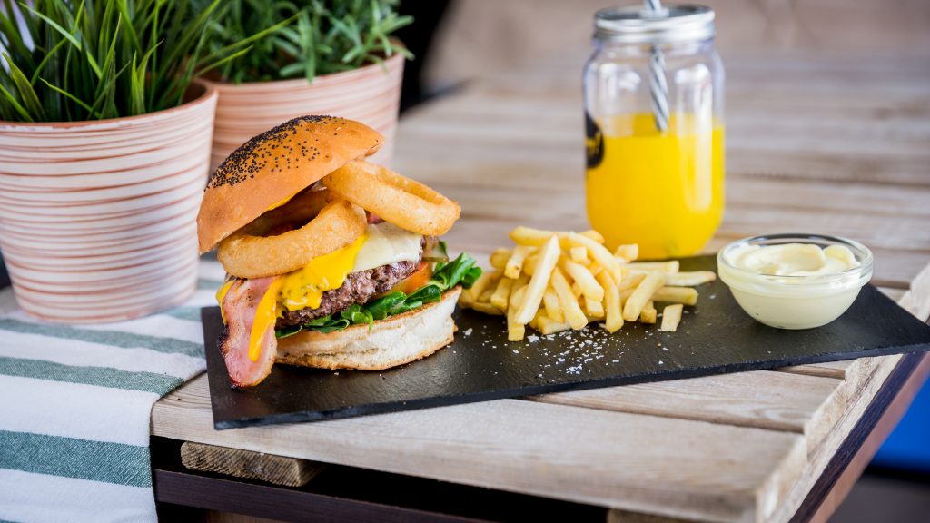 Vegan Burger Crispy Onion: Hamburguesa vegetal ,cebolla caramelizada, salsa, lechuga, tomate, cheddar vegano, mozzarella vegana, bacon vegano y aros crujientes de cebolla.