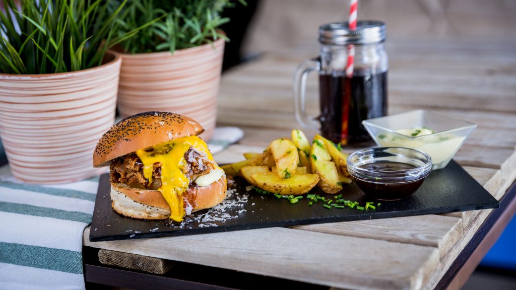 Hamburguesa de jack fruit cocinado a baja temperatura, desmechado y mezclado con salsa BBQ y bacon bits, con una base de patatas fritas finitas. Nuestra versión vegana del Pulled Pork Sandwich.